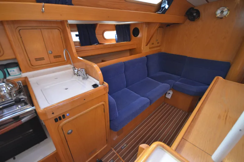 Monica Yacht Photos Pics Interior of 2006 Alubat Ovni 395 Centerboard yacht with blue seating and wooden cabinetry.