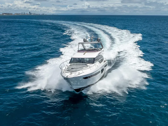  Yacht Photos Pics 2018 Princess F55 yacht cruising on open ocean with city skyline in background.