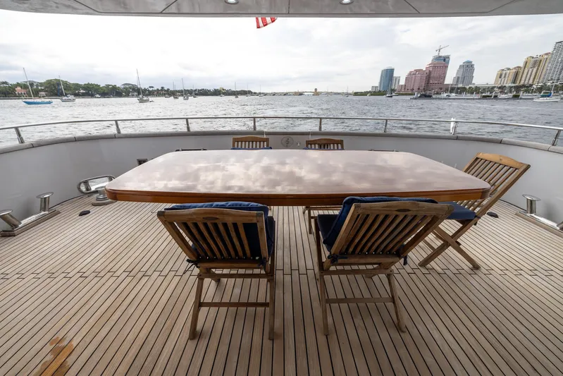  Yacht Photos Pics Deck view of 1999 Azimut 100 Jumbo yacht with wooden table and chairs, overlooking waterfront.