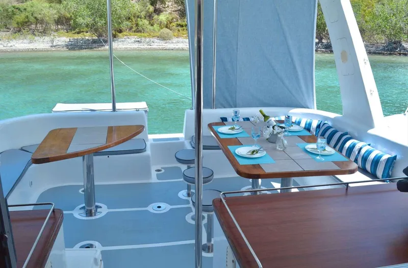 Chef De Mere Yacht Photos Pics Luxurious 2006 Royal Cape Catamarans 50 with elegant outdoor dining setup by turquoise waters.