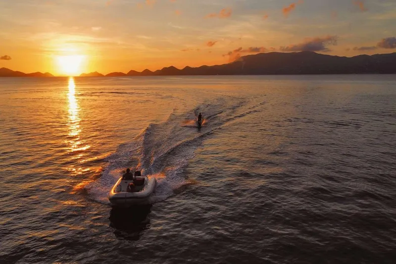Chef De Mere Yacht Photos Pics Boat towing a wakeboarder at sunset on calm ocean waters.