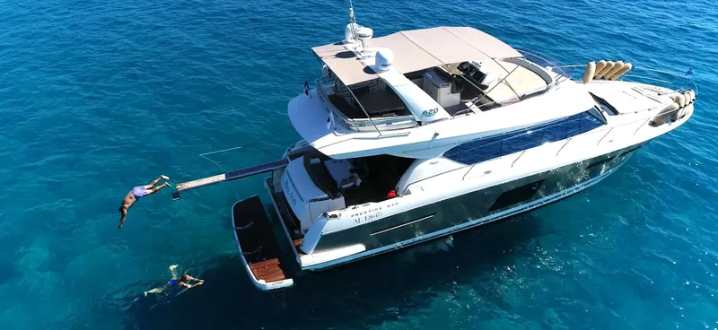  Yacht Photos Pics Aerial view of 2013 Prestige 620 yacht with people diving into clear blue water.