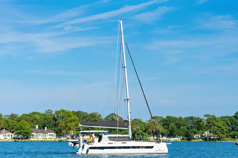 Carolina Red Yacht Photos Pics Sailing catamaran St Francis 460, 2024 model, cruising on a sunny day near lush shoreline.