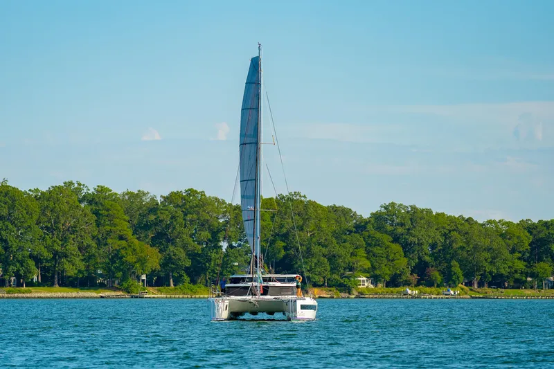 Carolina Red Yacht Photos Pics 2024 St Francis 460 catamaran sailing on a serene lake with lush green shoreline.