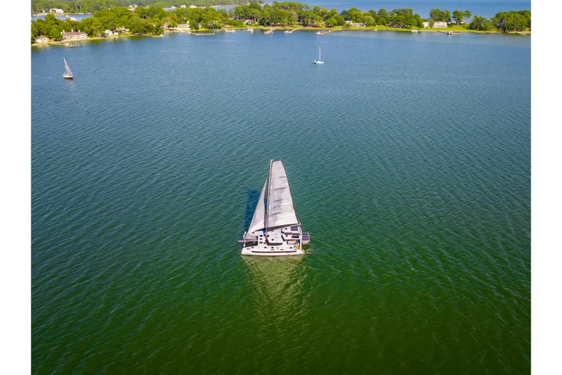 Carolina Red Yacht Photos Pics Sailboat St Francis 460, 2024 model, cruising on a serene lake with lush green surroundings.