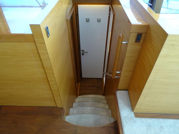 Quintessa Yacht Photos Pics Staircase leading to a door inside a 2014 Horizon PC52 yacht, featuring wooden paneling.