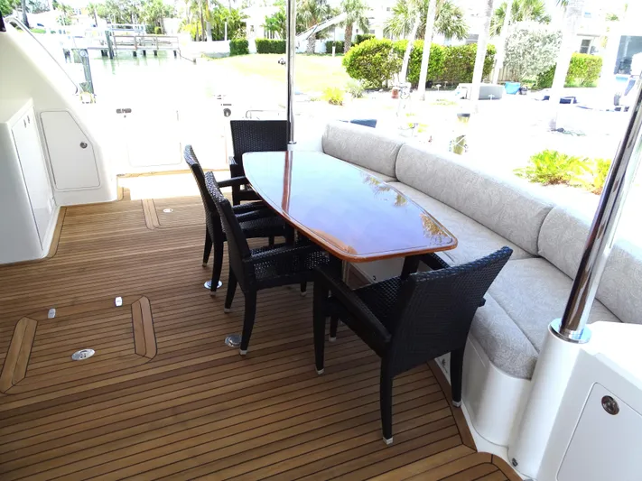 Quintessa Yacht Photos Pics Outdoor seating area on 2014 Horizon PC52 yacht with wooden table and chairs.