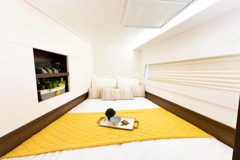 Southern Wild Yacht Photos Pics Cozy bedroom interior of 2018 Lagoon 40 yacht with yellow accents and decorative plants.