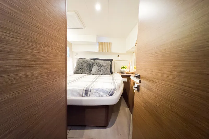 Southern Wild Yacht Photos Pics Cozy bedroom interior of 2018 Lagoon 40 catamaran with plush bedding and wooden accents.