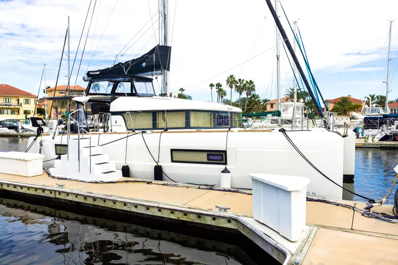 Southern Wild Yacht Photos Pics 2018 Lagoon 40 catamaran docked at a marina, surrounded by other boats and palm trees.