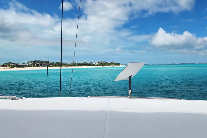 Southern Wild Yacht Photos Pics Lagoon 40 catamaran sailing near tropical beach, turquoise waters, clear blue sky, 2018 model.