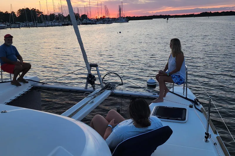 Southern Wild Yacht Photos Pics People relaxing on a 2018 Lagoon 40 catamaran at sunset, near a marina.