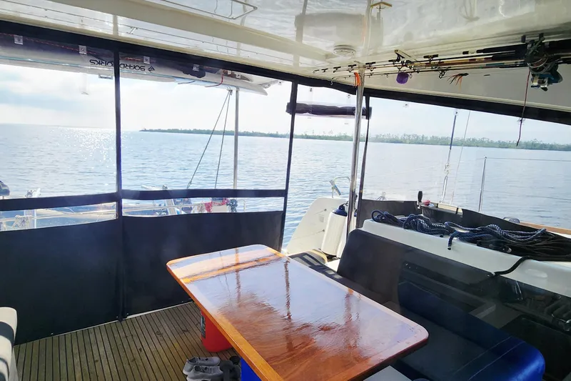 Southern Wild Yacht Photos Pics 2018 Lagoon 40 catamaran interior with ocean view, featuring a polished wooden table and seating area.