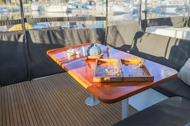 Southern Wild Yacht Photos Pics Luxurious Lagoon 40 catamaran deck with wooden table, backgammon set, and decorative items, 2018 model.