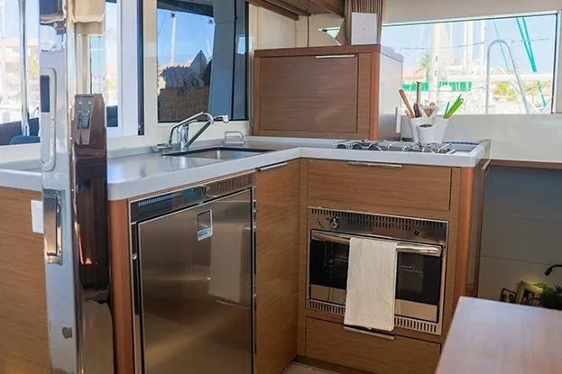 Southern Wild Yacht Photos Pics Modern kitchen interior of 2018 Lagoon 40 catamaran with wood cabinetry and stainless steel appliances.