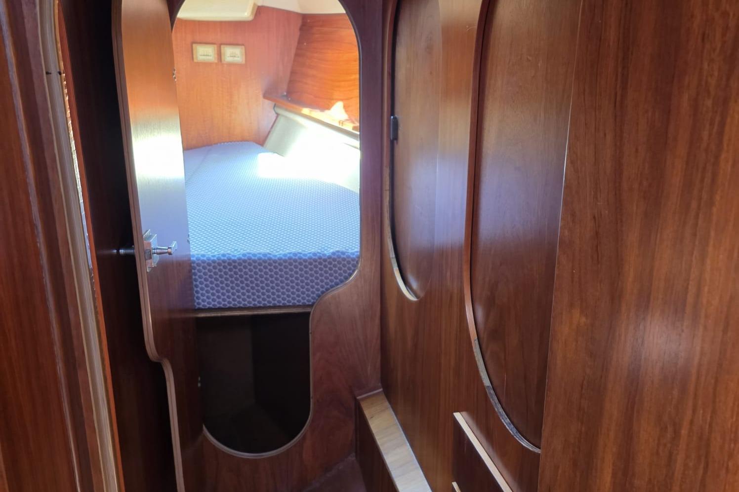 Interior cabin of 1981 Comar Comet 11 sailboat with wooden finish and cozy bed.