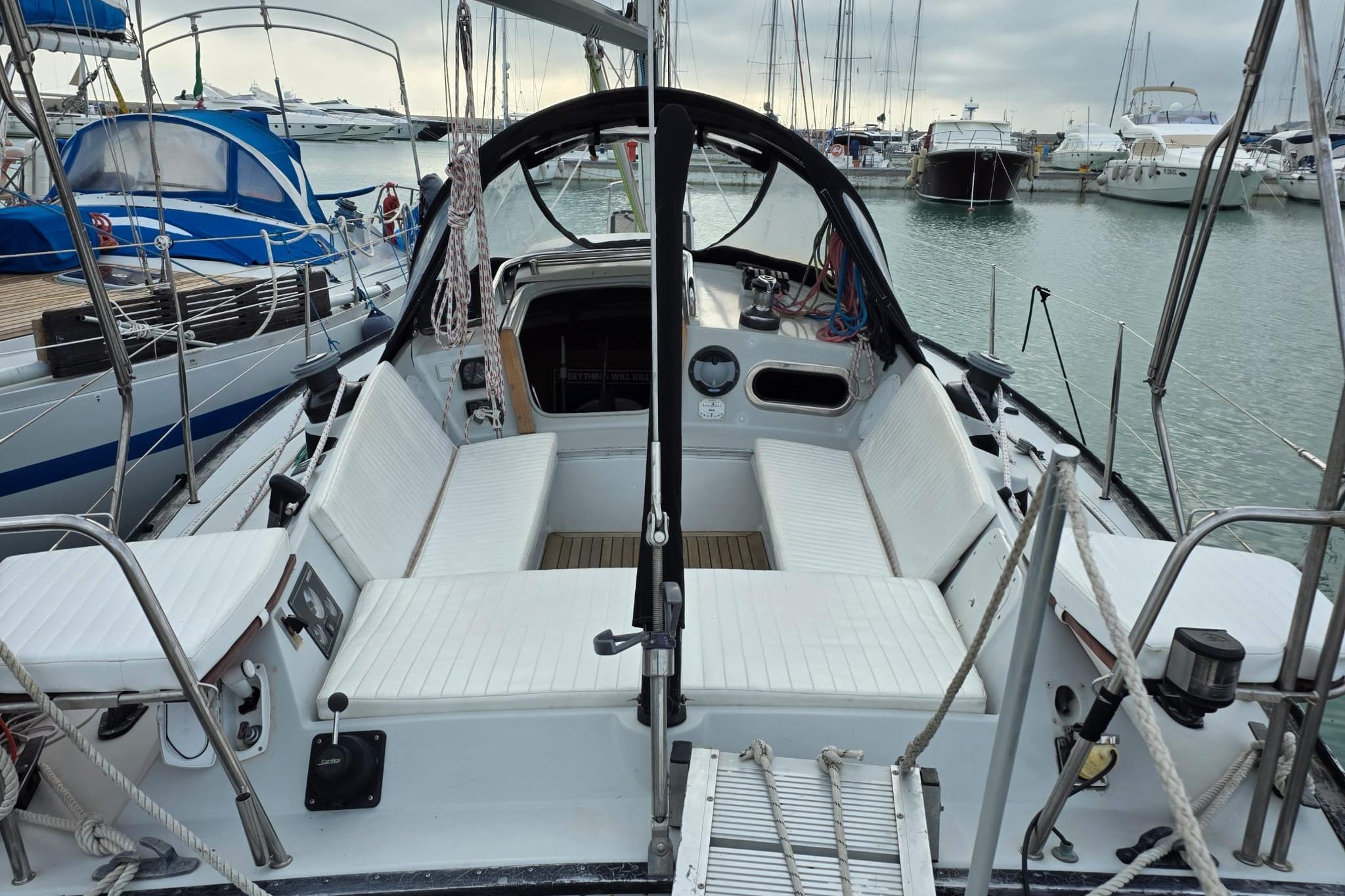 1981 Comar Comet 11 sailboat cockpit with white seating, docked in a marina.