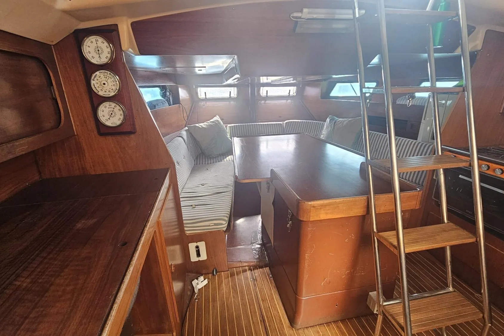 Interior of 1981 Comar Comet 11 sailboat with wooden furnishings and striped seating.
