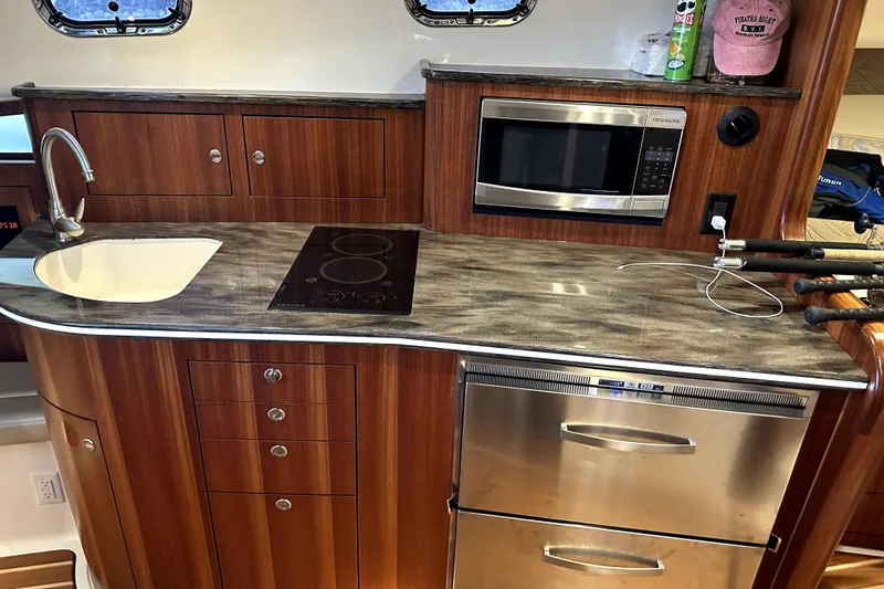 Change Of Pace Yacht Photos Pics Kitchen area in a 2014 PURSUITE 385 boat with sink, stove, and microwave.