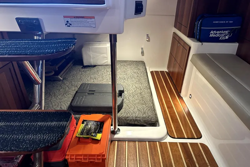 Change Of Pace Yacht Photos Pics Interior of 2014 PURSUITE 385 boat with storage, medical kit, and patterned bedding.