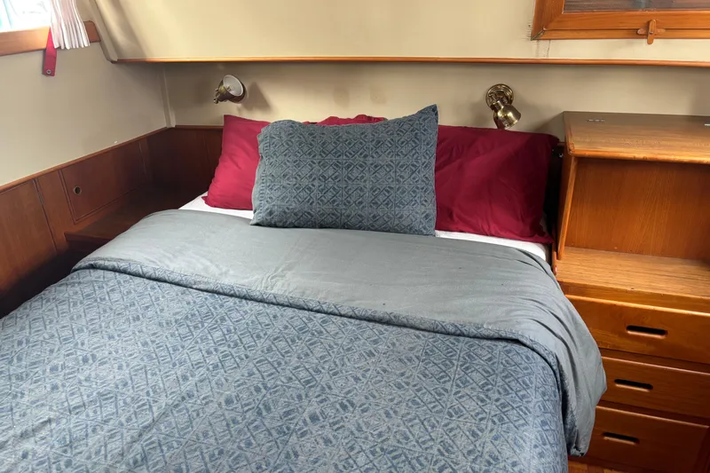  Yacht Photos Pics Cozy bedroom in 1991 Grand Banks 36 Classic yacht with blue bedding and wooden cabinetry.