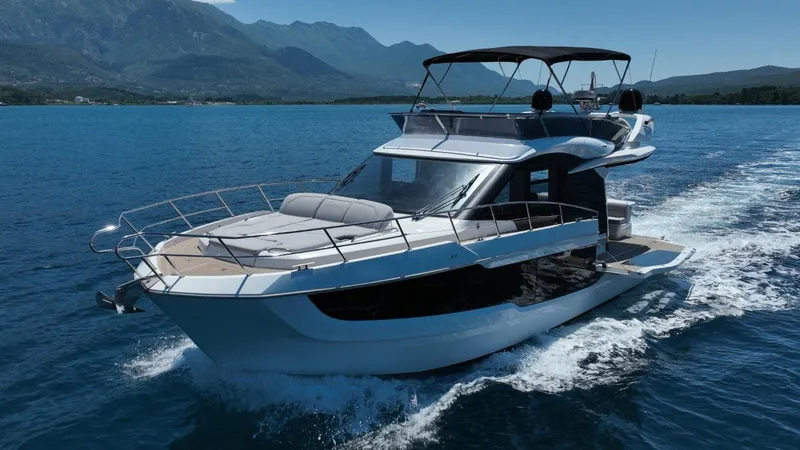  Yacht Photos Pics 2024 Galeon 440 Fly yacht cruising on blue waters with mountainous backdrop.