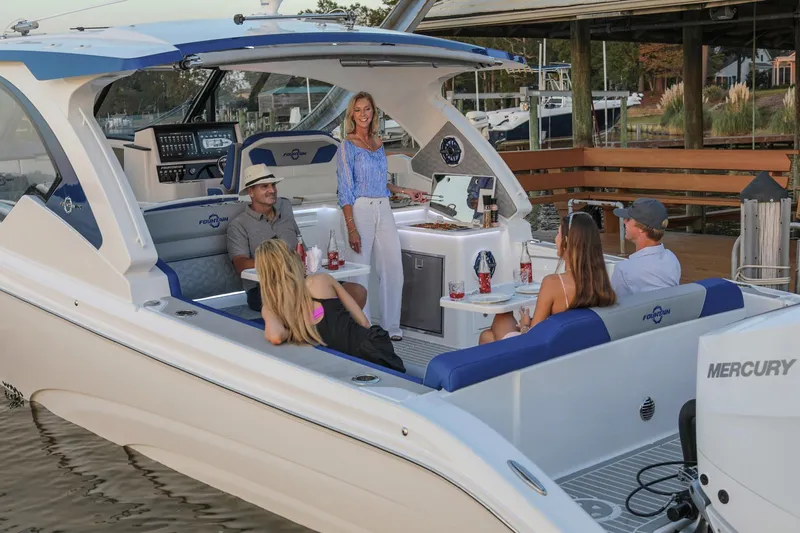  Yacht Photos Pics 2025 Fountain 39 DX boat with people relaxing onboard, docked near a marina.