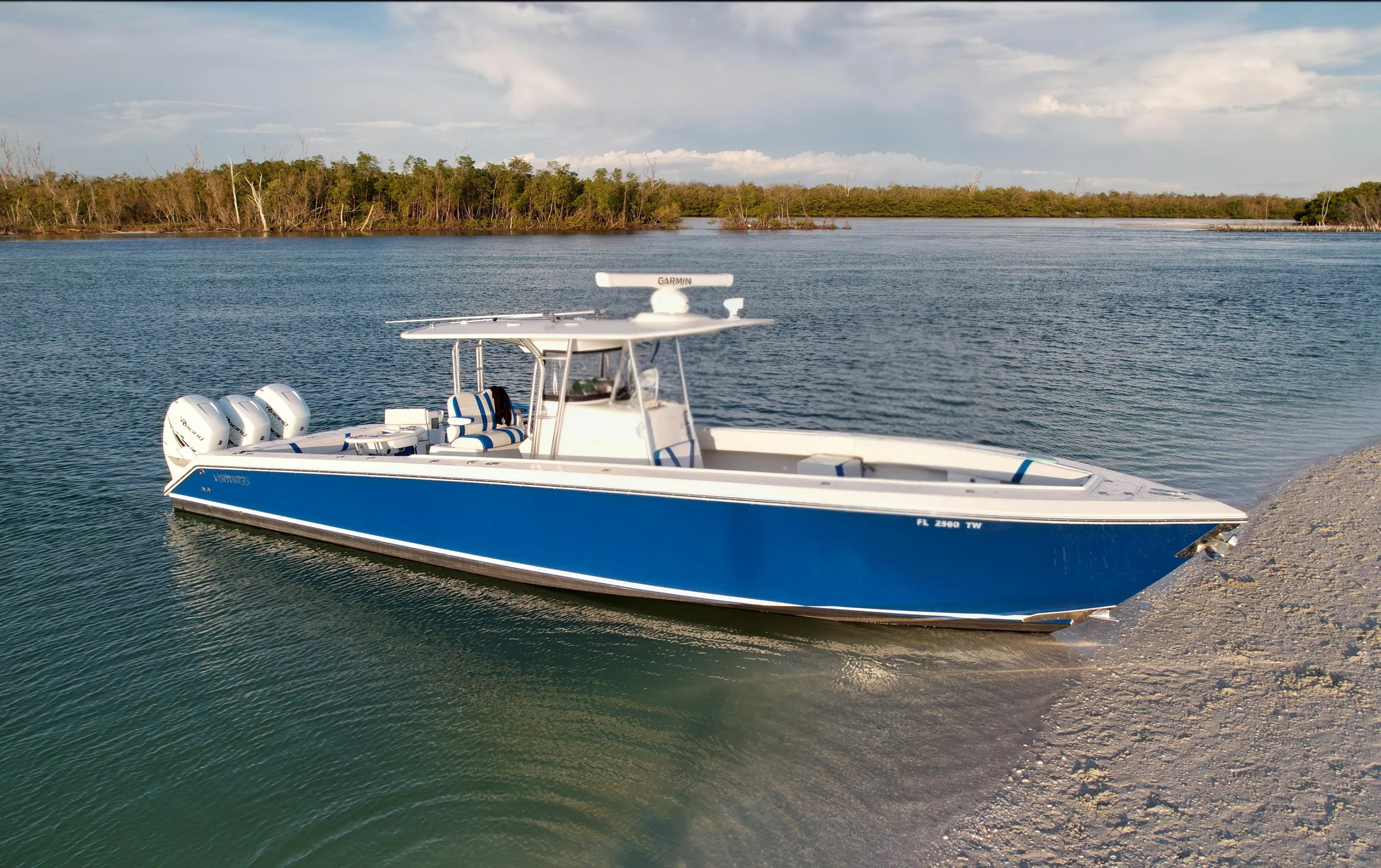 2016 Venture 39 Forward Seating boat in serene waters near a sandy shore.