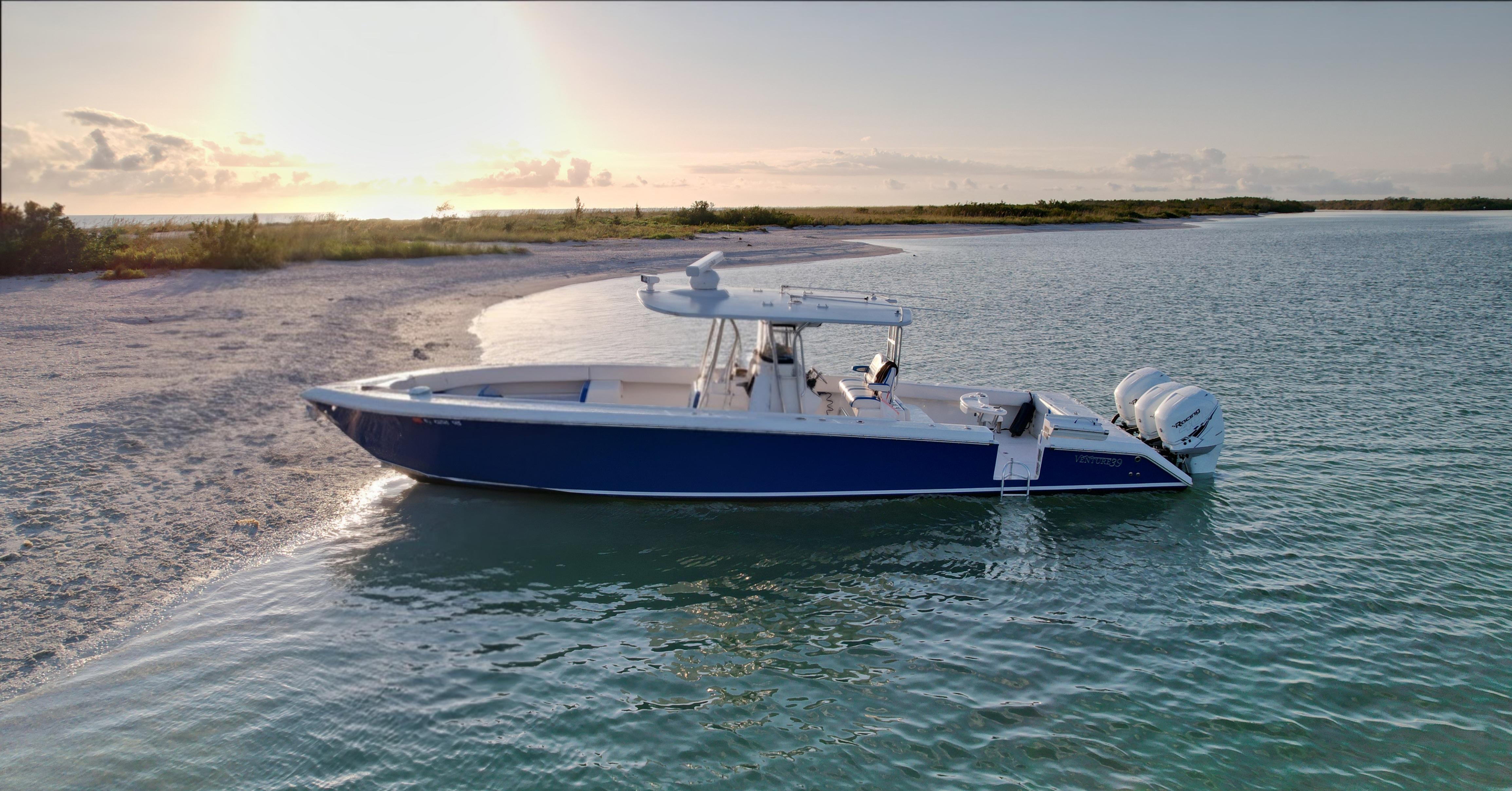 2016 Venture 39 Forward Seating boat anchored near a sandy beach at sunset.