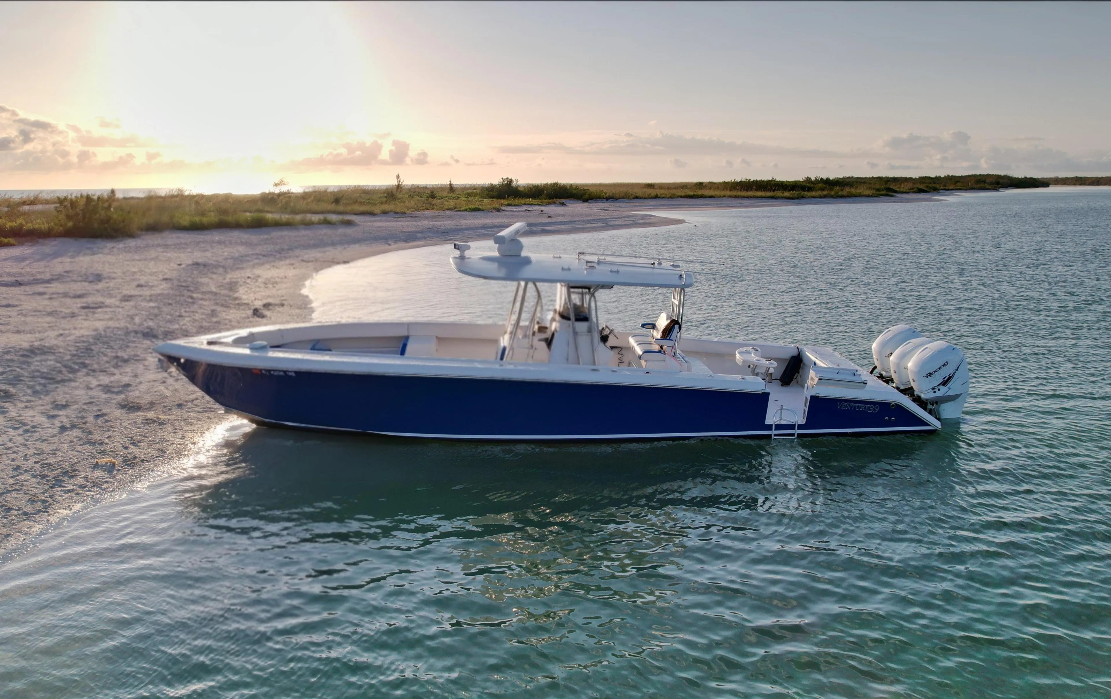 2016 Venture 39 Forward Seating boat anchored near a sandy beach at sunset.