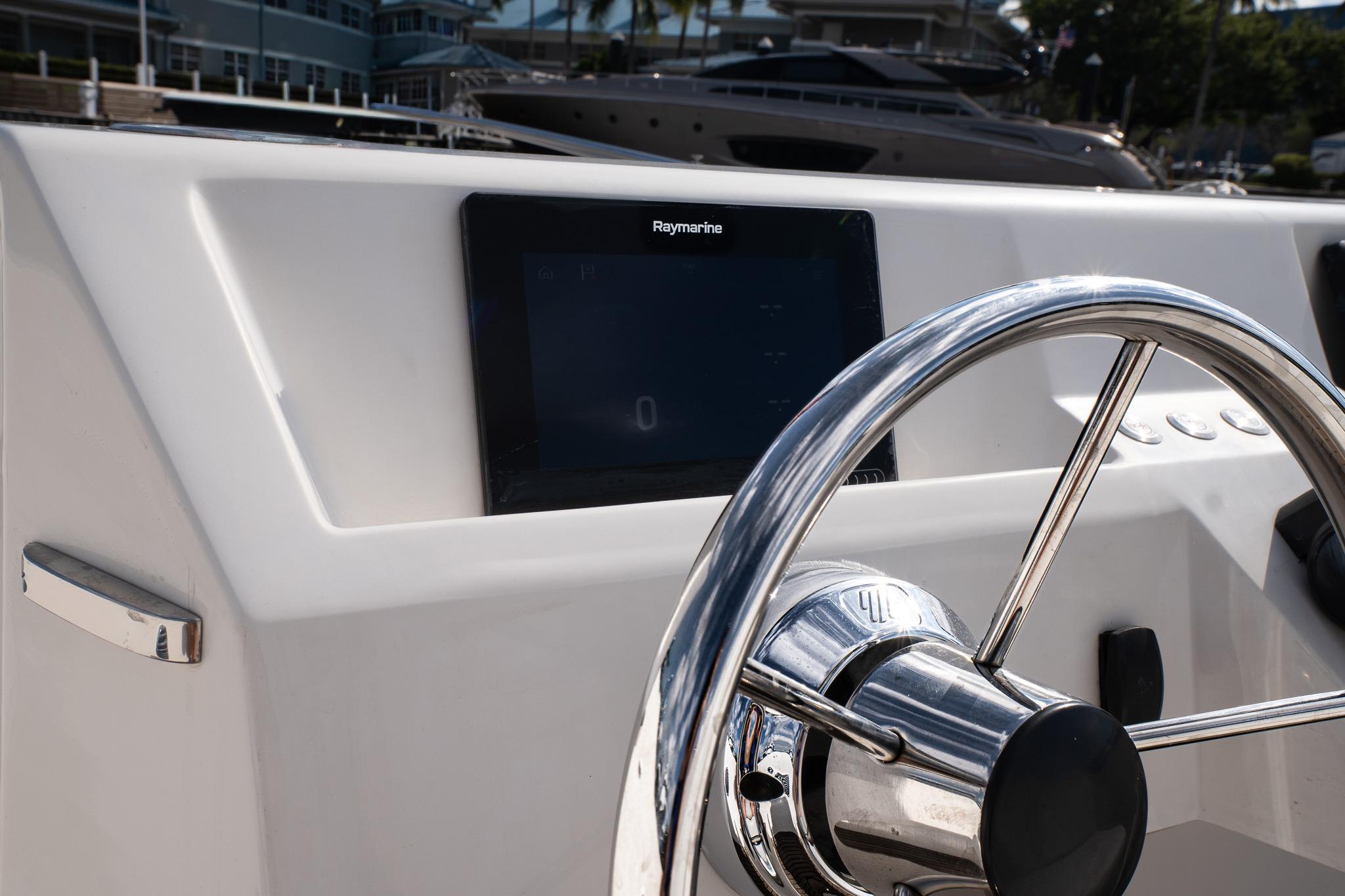 Steering wheel and dashboard of 2022 Rand 23 Mana boat, featuring Raymarine display.
