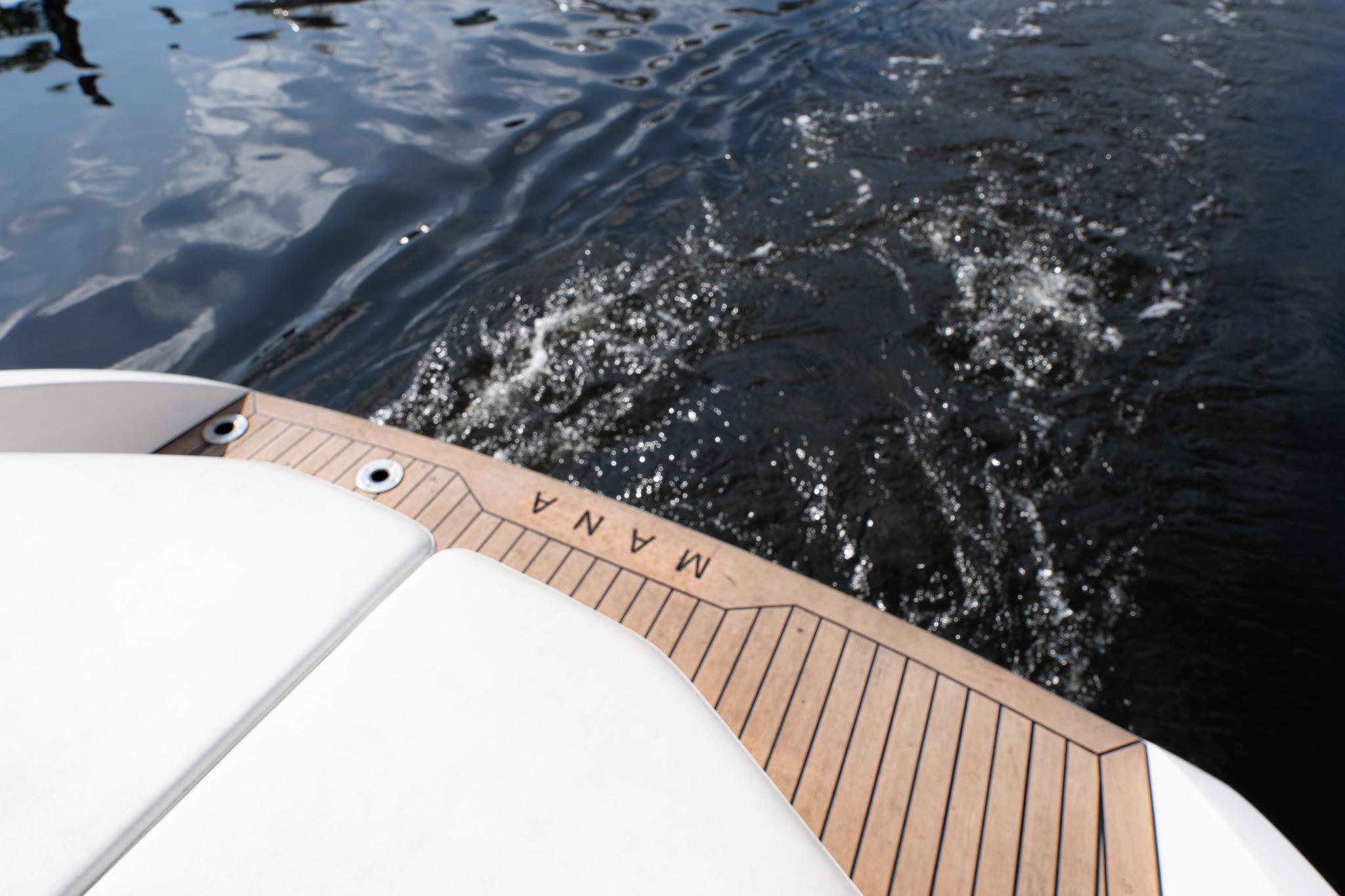 Sleek 2022 Rand 23 Mana boat on water, showcasing elegant wooden deck design.