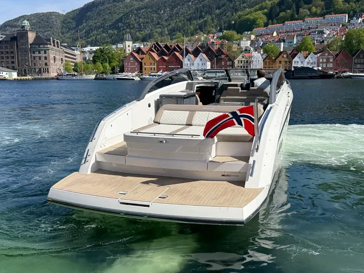  Yacht Photos Pics 2023 Windy 37 Shamal yacht with Norwegian flag, cruising near colorful waterfront buildings.