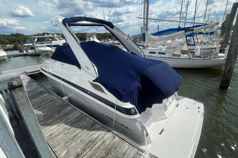  Yacht Photos Pics 2023 Regal 28 Express boat docked with blue cover, marina background.