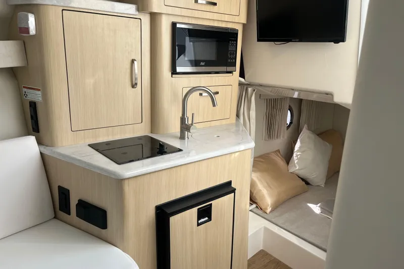  Yacht Photos Pics 2023 Regal 28 Express boat interior with kitchenette, microwave, and cozy sleeping area.