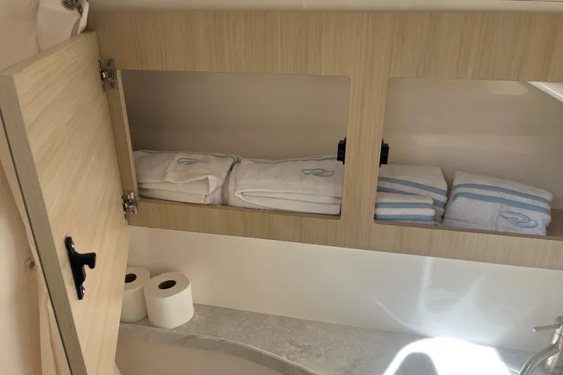 Yacht Photos Pics 2023 Regal 28 Express bathroom cabinet with towels and toilet paper.