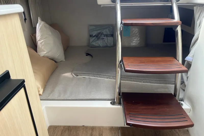  Yacht Photos Pics 2023 Regal 28 Express cabin interior with wooden steps and cozy bedding.