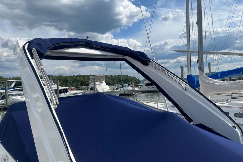  Yacht Photos Pics 2023 Regal 28 Express boat with blue cover docked at marina under cloudy sky.