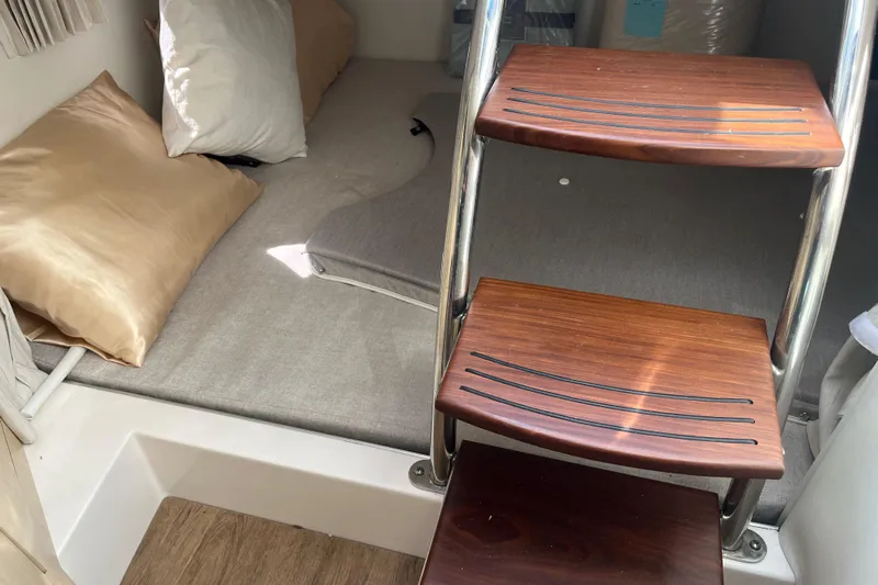  Yacht Photos Pics Interior cabin of 2023 Regal 28 Express boat with wooden steps and cozy bedding.