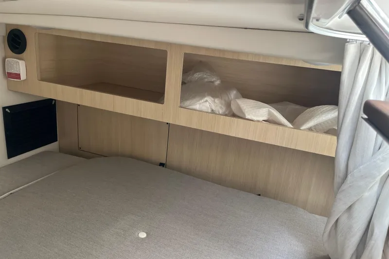  Yacht Photos Pics 2023 Regal 28 Express cabin interior with wooden storage shelves and bedding.