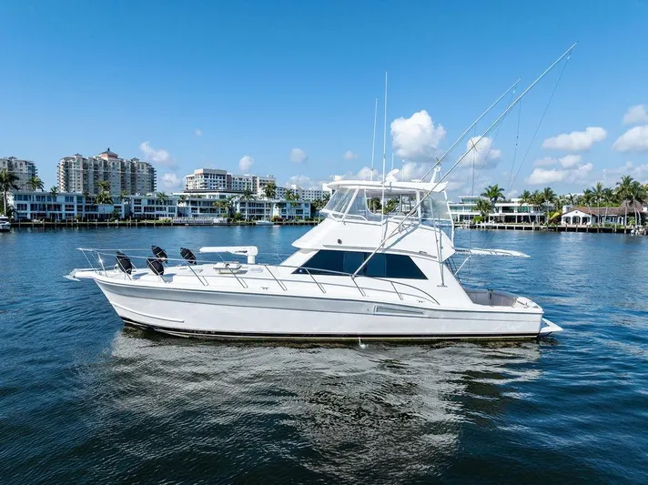  Yacht Photos Pics 2001 Riviera 48 yacht on calm water with cityscape background.