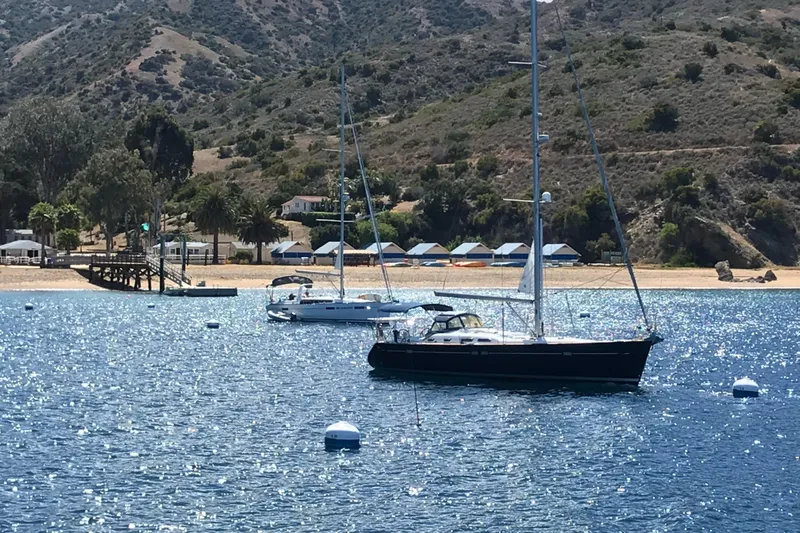 Dionysus Yacht Photos Pics Sailboats anchored near a scenic coastline, featuring a 2003 Beneteau Oceanis Clipper 473.