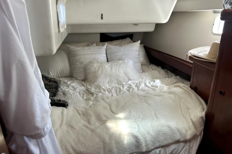 Dionysus Yacht Photos Pics Cozy cabin interior of 2003 Beneteau Oceanis Clipper 473 with plush bedding and wooden accents.