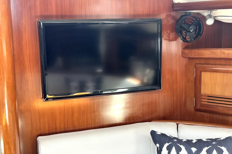 Dionysus Yacht Photos Pics Interior of 2003 Beneteau Oceanis Clipper 473 with TV and fan on wooden paneling.