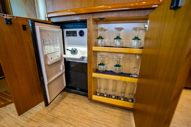 Last Call Yacht Photos Pics Open cabinet with mini fridge and glassware on Viking 70 Enclosed Bridge yacht, 2011 model.