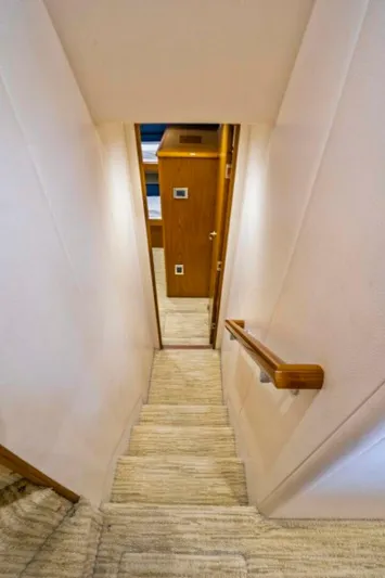 Last Call Yacht Photos Pics Stairway inside 2011 Viking 70 Enclosed Bridge yacht, featuring wooden handrails and carpeted steps.