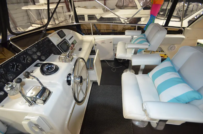 Suite Forty Six Yacht Photos Pics 1989 Silverton Aft Cabin 46 yacht helm with white seating and striped cushions.