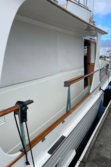  Yacht Photos Pics 1980 Grand Banks 42 Europa yacht docked, showcasing sleek white exterior and wooden railings.