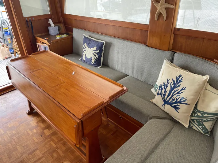  Yacht Photos Pics Interior of 1980 Grand Banks 42 Europa with wooden table and nautical-themed cushions.