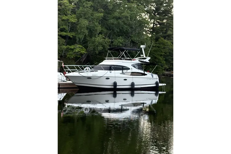  Yacht Photos Pics 2003 Regal Commodore 3880 yacht docked on calm water, surrounded by lush greenery.